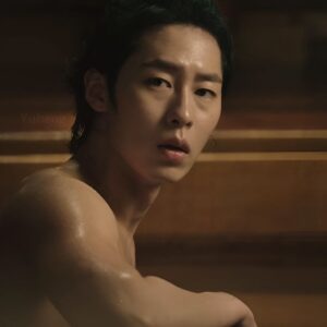 Lee Jae Wook smiling confidently at a press conference, wearing a stylish black suit.